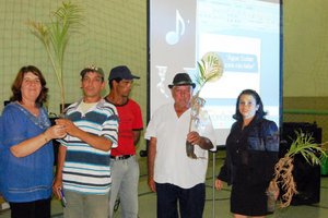 A Secretária M. de Educação, Maria Aparecida Noronha (esq.), e a Presidente do Sindicato dos Trabalhadores Rurais, Silvana Damasceno (dir.), procedendo com a entrega de mudas.